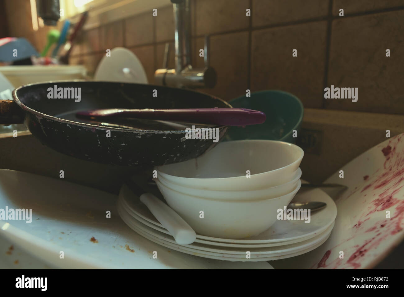 A Messy Pile of Dirty Dishes And Utensils In Kitchen Sink Stock Photo