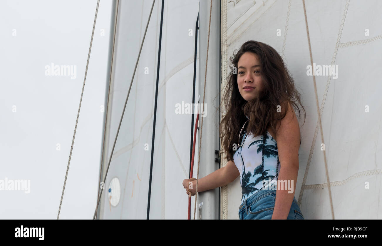 young teen girl standing on the boom of a sailboat with sails behind her Stock Photo Alamy
