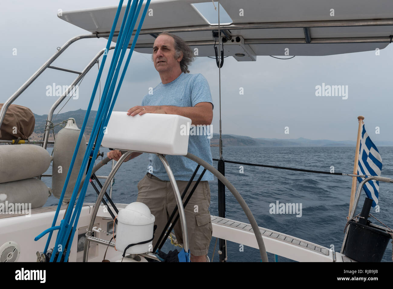 Senior Citizen at the helm of a sailboat off the coast of Lesvos Stock Photo
