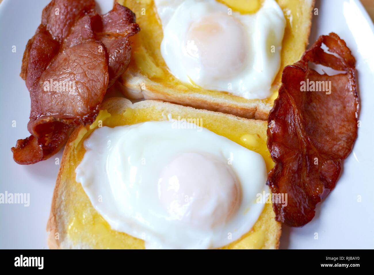 Two poached eggs with bacon on white buttered toast Stock Photo