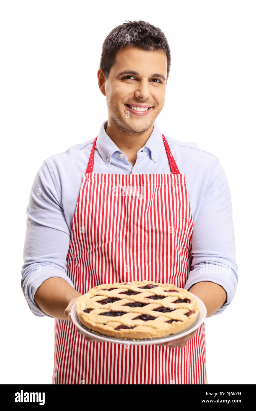 Smiling young man with an apron holdin a sweet cherry pie isolated on white background Stock Photo