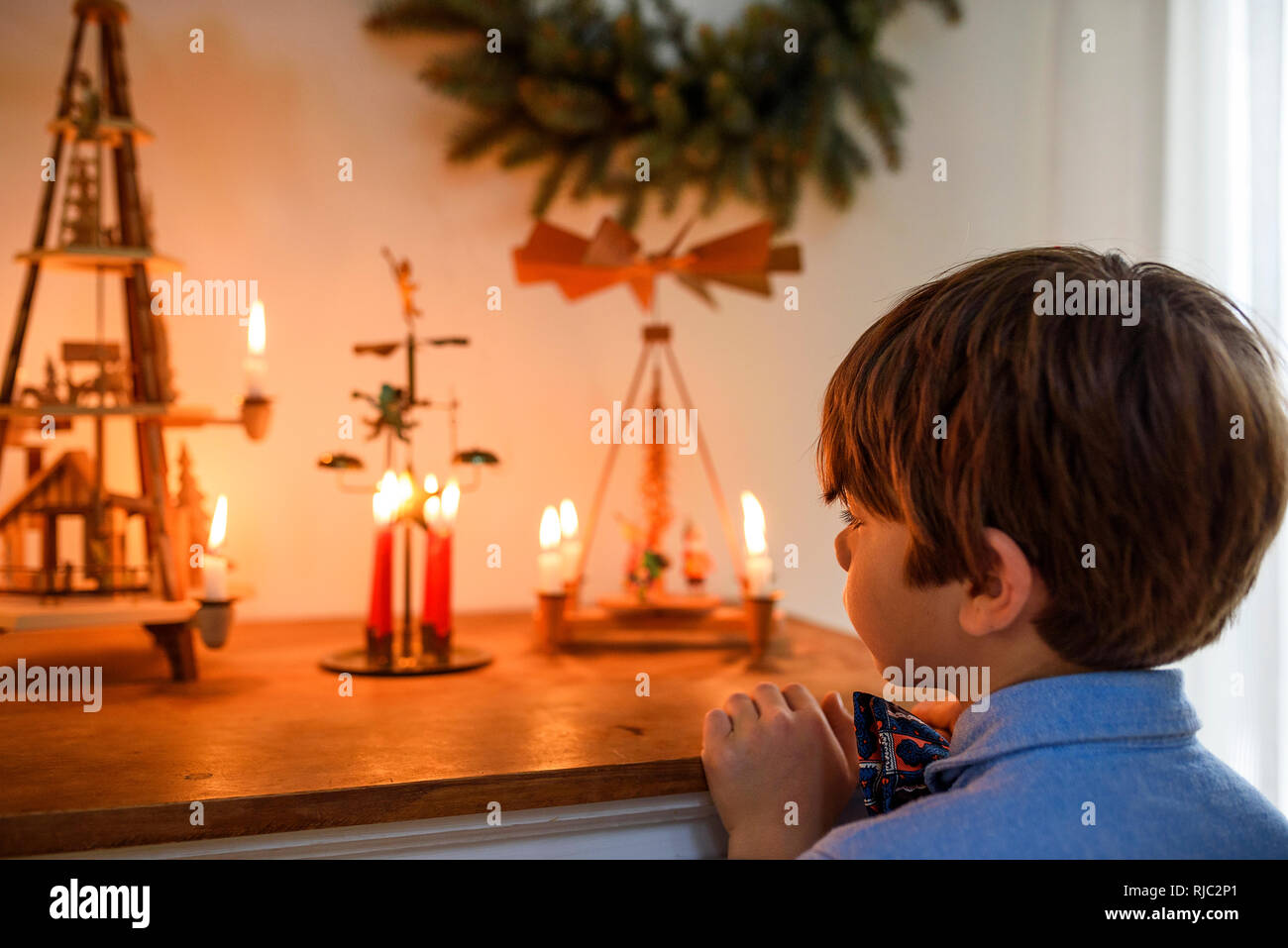 Boy standing in front of a sideboard looking at Christmas decorations Stock Photo