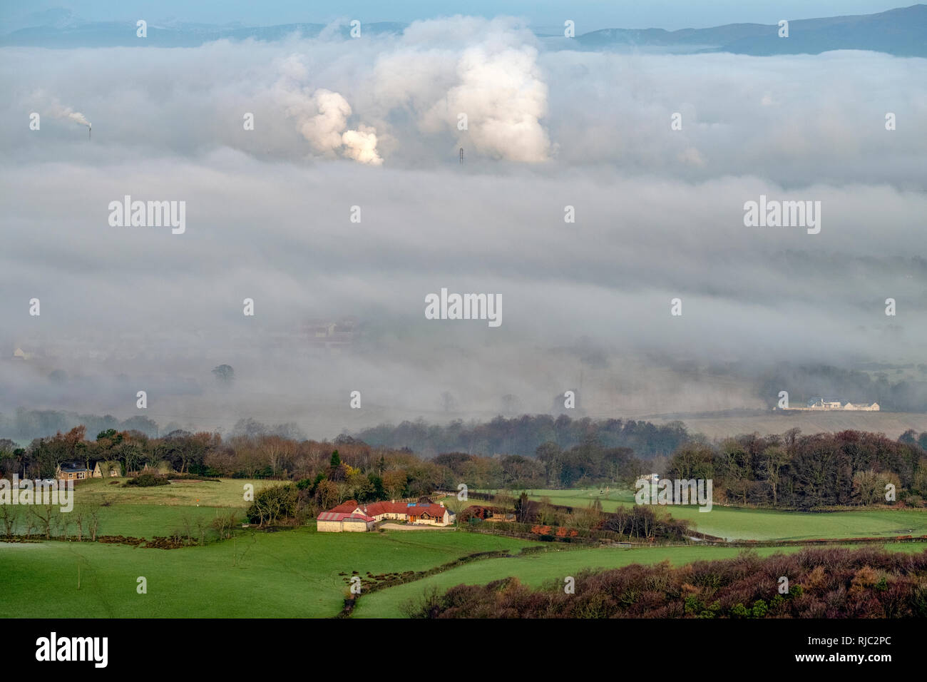 View of a farmhouse in the forth valley and showing emissions from the Grangemouth oil refinery in the distance showing through the morning mist. Stock Photo