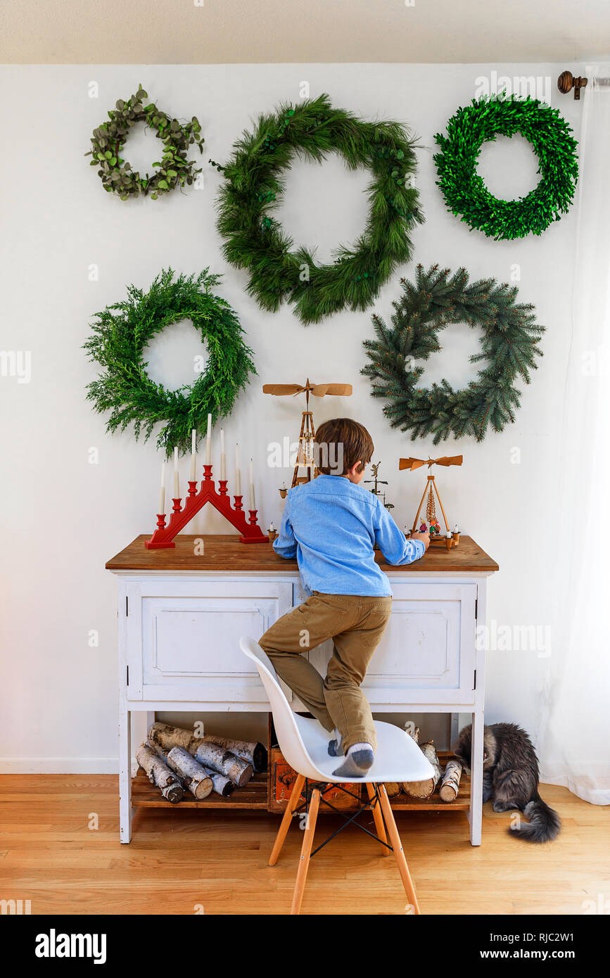 Boy standing on a chair in front of a sideboard Stock Photo
