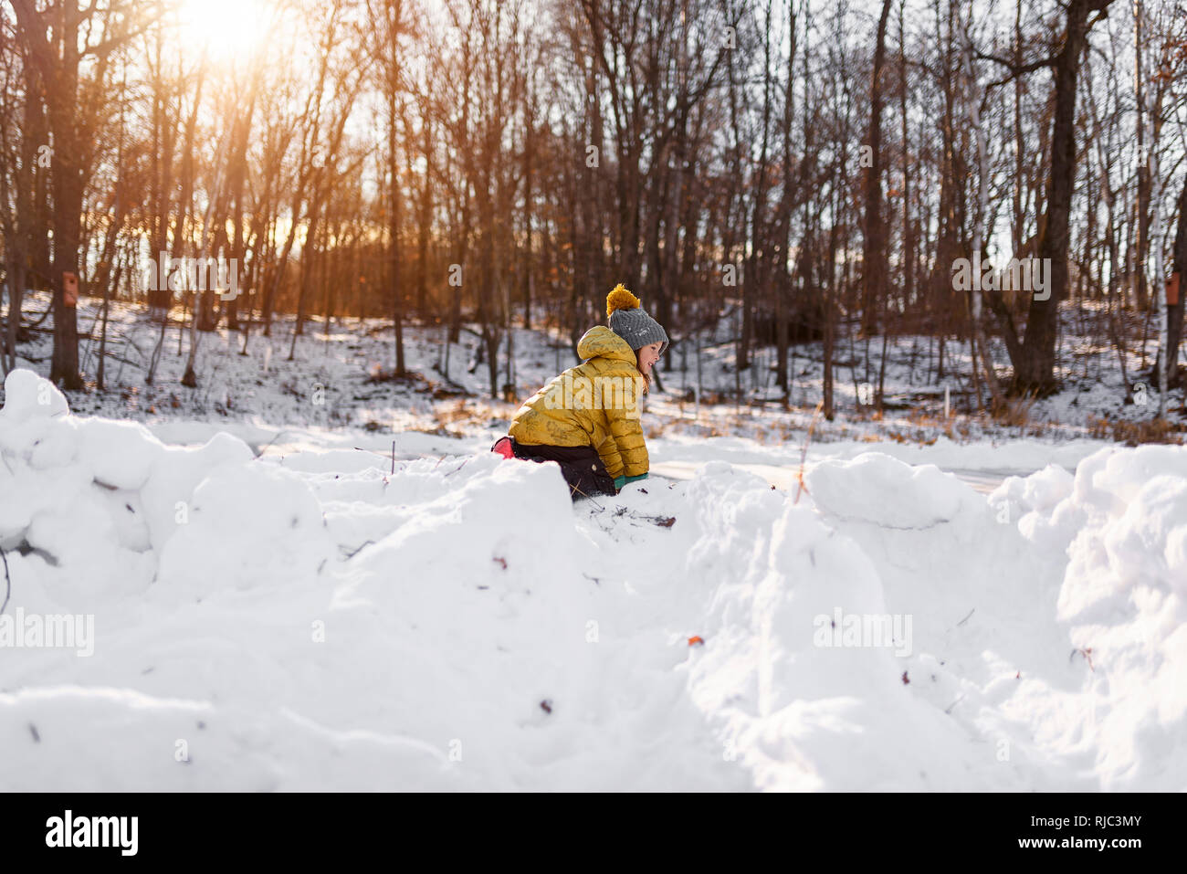 Smiling girl building a snow fort, United States Stock Photo