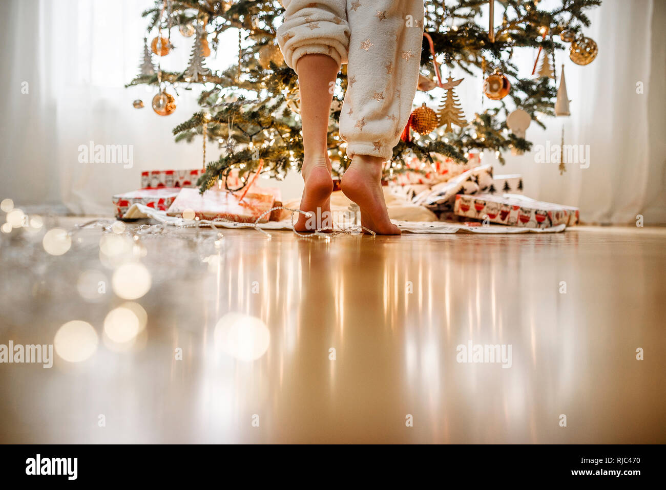 Close-up of a girl's legs standing by a Christmas tree Stock Photo