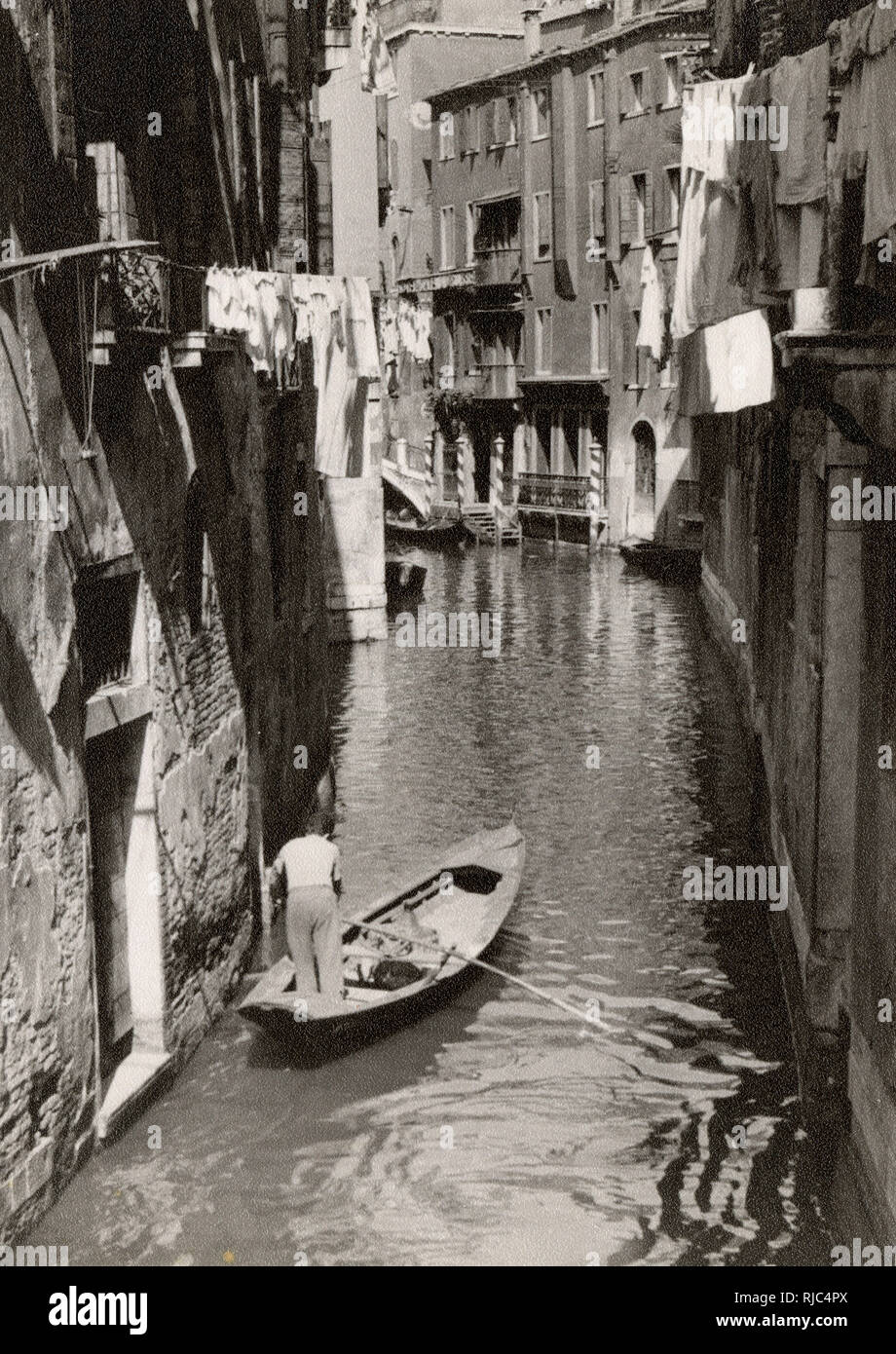 A small back canal, Venice, Italy - A local man off shopping Stock Photo