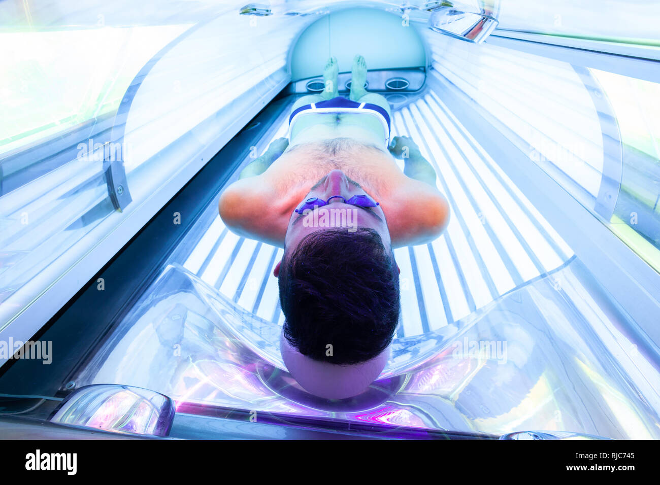 Young Thin Man At Solarium In Beauty Salon. Full tanning bed. Stock Photo