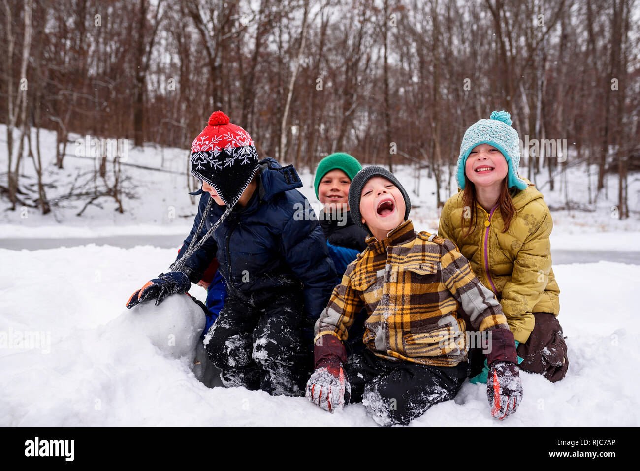 Four children sitting in the snow, Wisconsin, United States Stock Photo