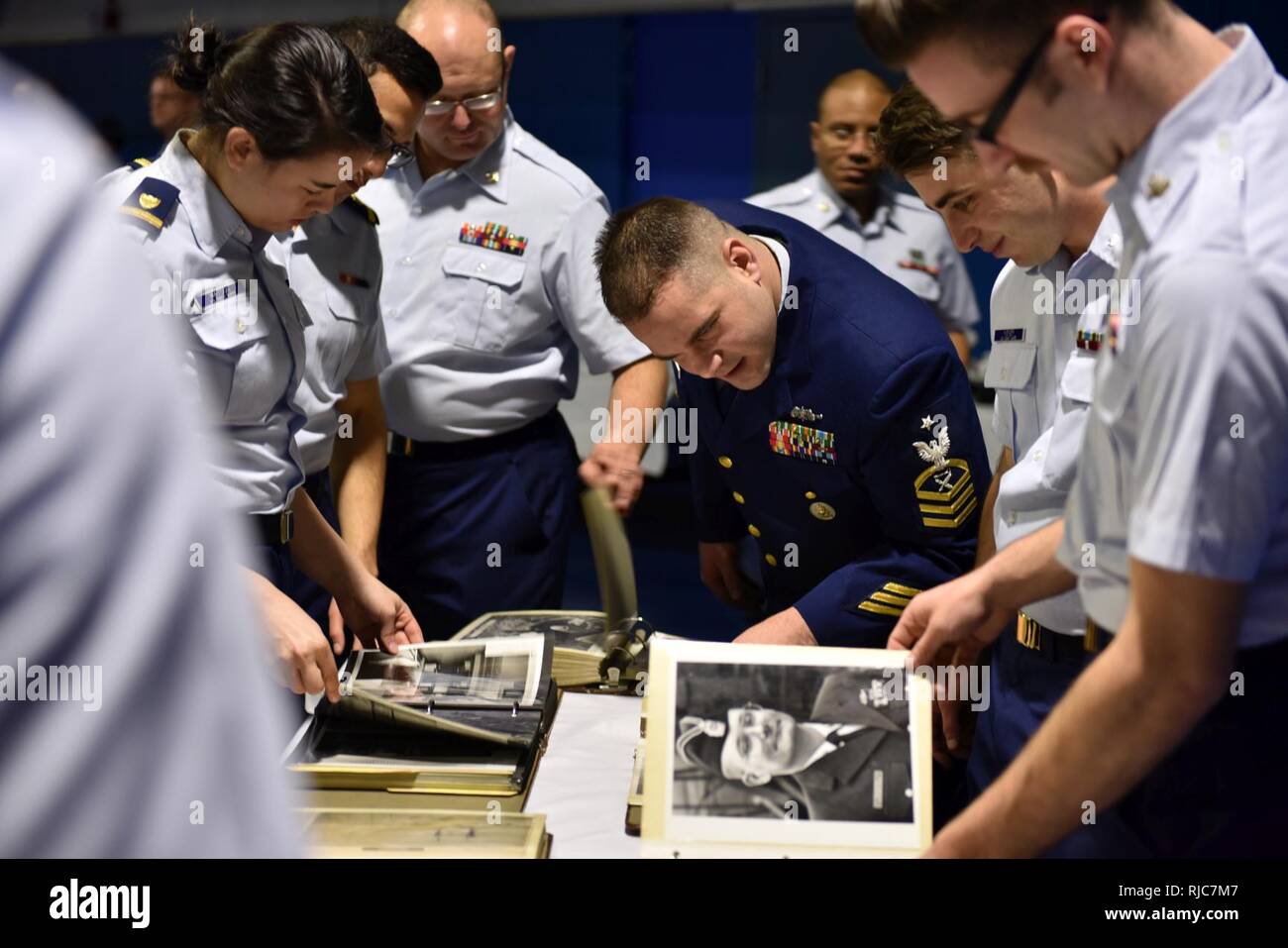 Coast Guard Cutter Mellon crewmembers look through photo albums prior to a ceremony held in the Base Seattle gymnasium on Jan. 9, 2018, which celebrated the cutter’s 50 years of service. The Mellon was designed to help crewmembers perform each of the Coast Guard’s missions including search and rescue, defense operations, law enforcement and environmental protection. Stock Photo