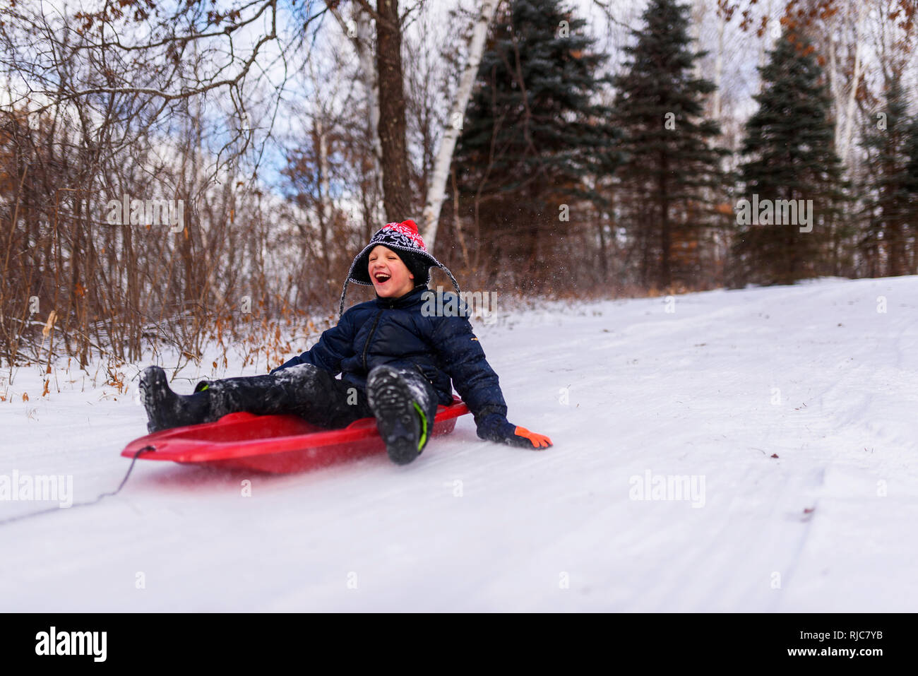 Boy on a sledge laughing, Wisconsin, United States Stock Photo