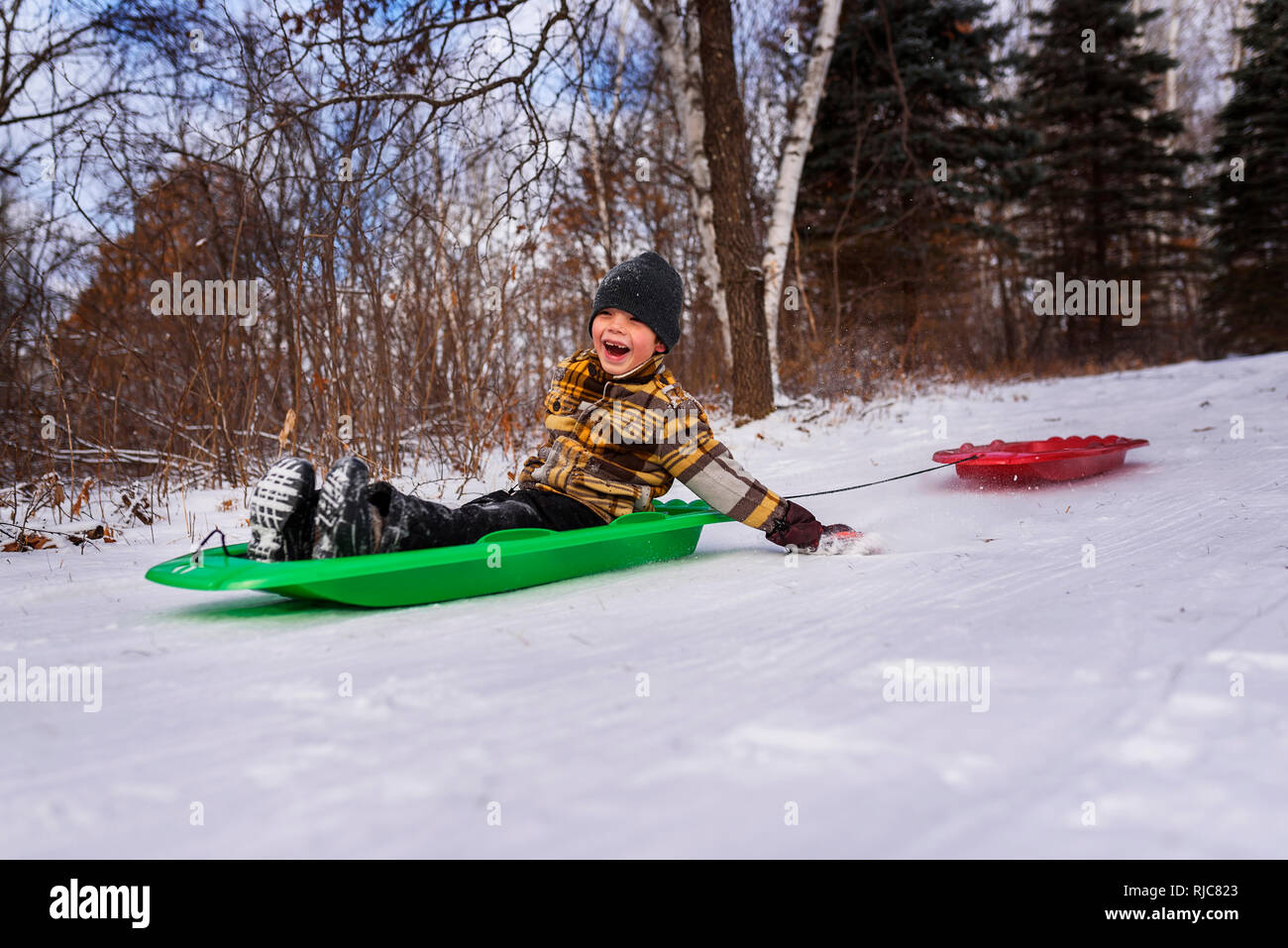 Boy on a sledge laughing, Wisconsin, United States Stock Photo