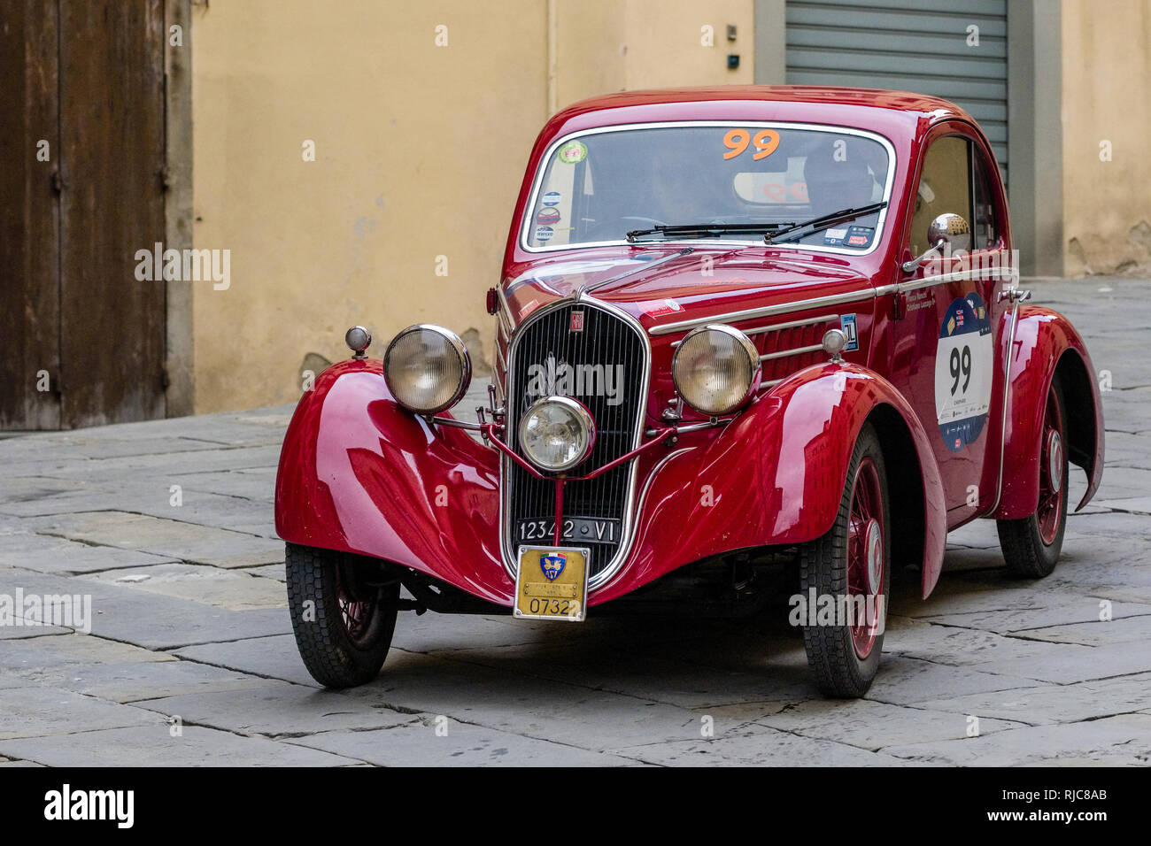 A vintage car, joining the rallye Mille Miglia, driving through the small streets of the medieval town Stock Photo