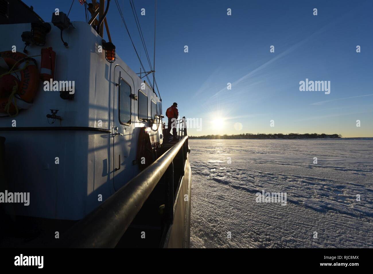 The crew of Coast Guard Cutter Shackle, a 65-foot Small Harbor Tug, breaks ice Wednesday, Jan. 10, 2018 near Logan International Airport in Boston Harbor. Shackle is capable of breaking up to 12 inches of ice. Stock Photo