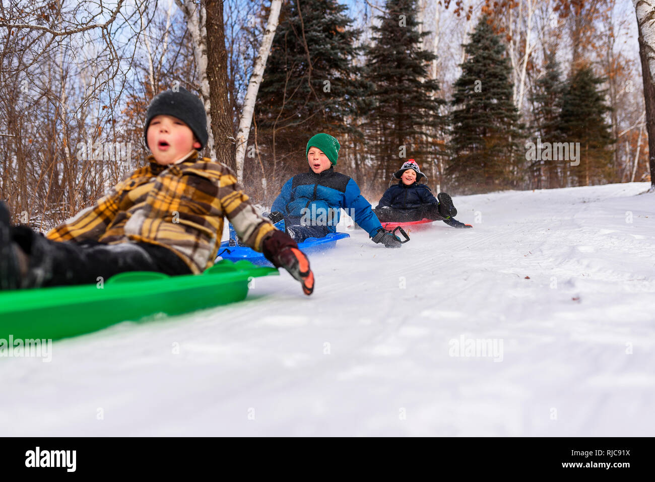 Three boys on a sledge laughing, Wisconsin, United States Stock Photo
