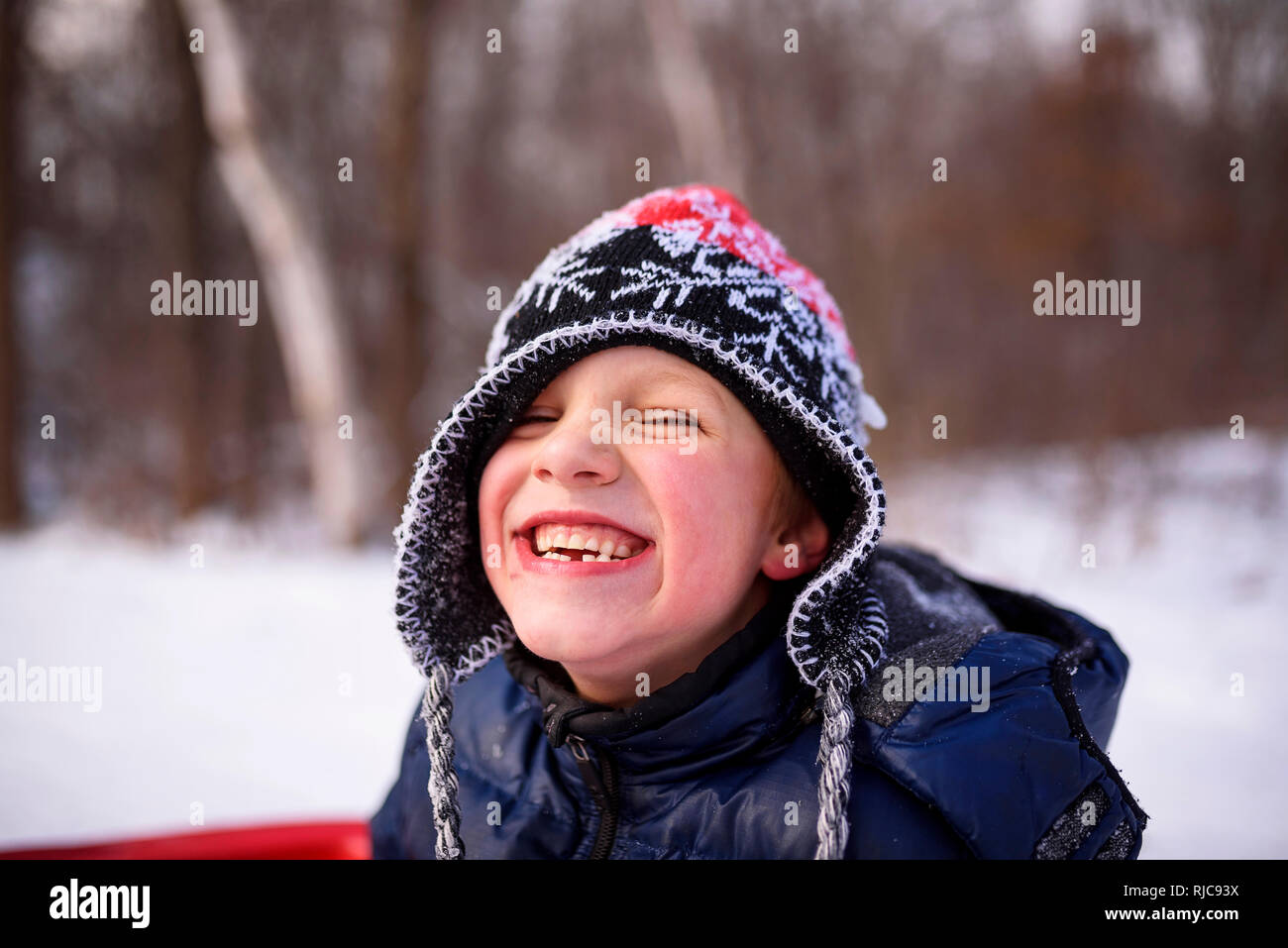 Portrait of a boy on a sledge laughing, Wisconsin, United States Stock Photo