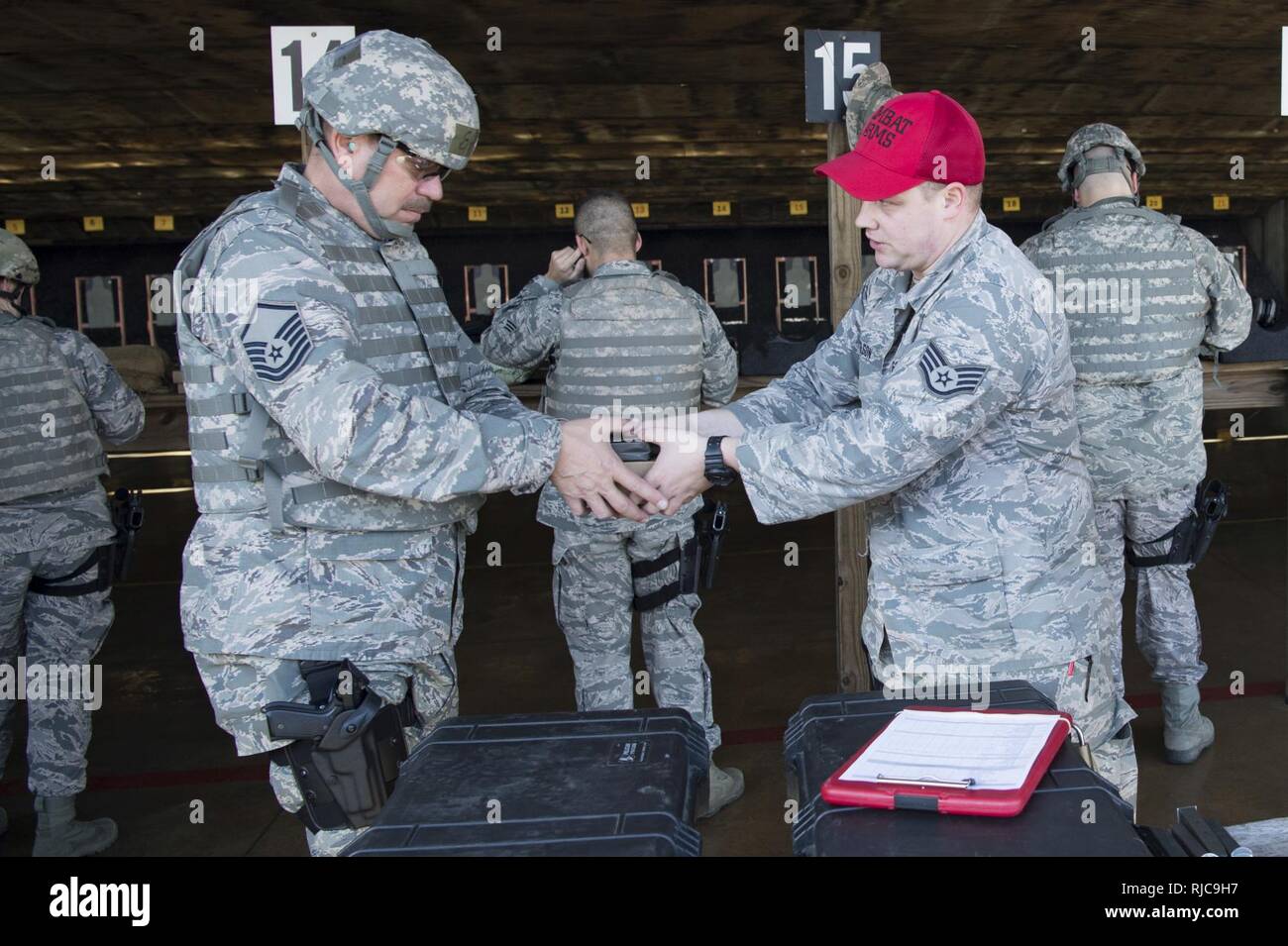 U.S. Air Force Staff Sgt. Corey Wilson, a Combat Arms Training and Maintenance Instructor with the 130th Security Forces Squadron, hands U.S. Air Force Master Sgt. Paul Ruddle ammunition for an M4 rifle Jan. 10, 2018 at the Combat Arms Training and Maintenance Facility for the Combat Readiness Training Center, Gulfport, Miss. Airmen must be weapon qualified every 18 months to ensure mission readiness. Stock Photo