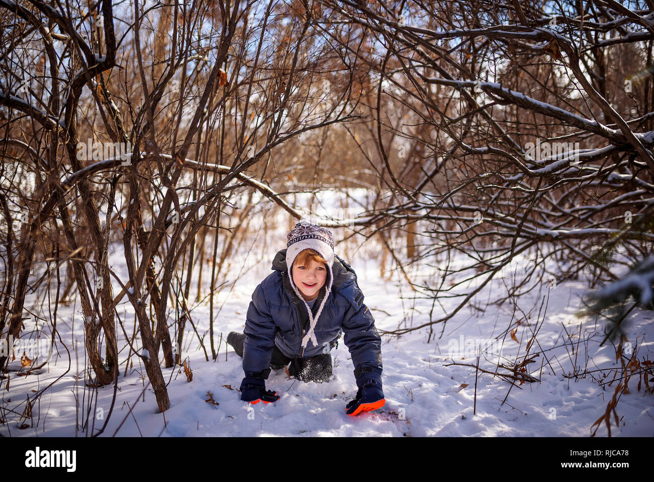 Boy crawling through the snow, Wisconsin, United States Stock Photo