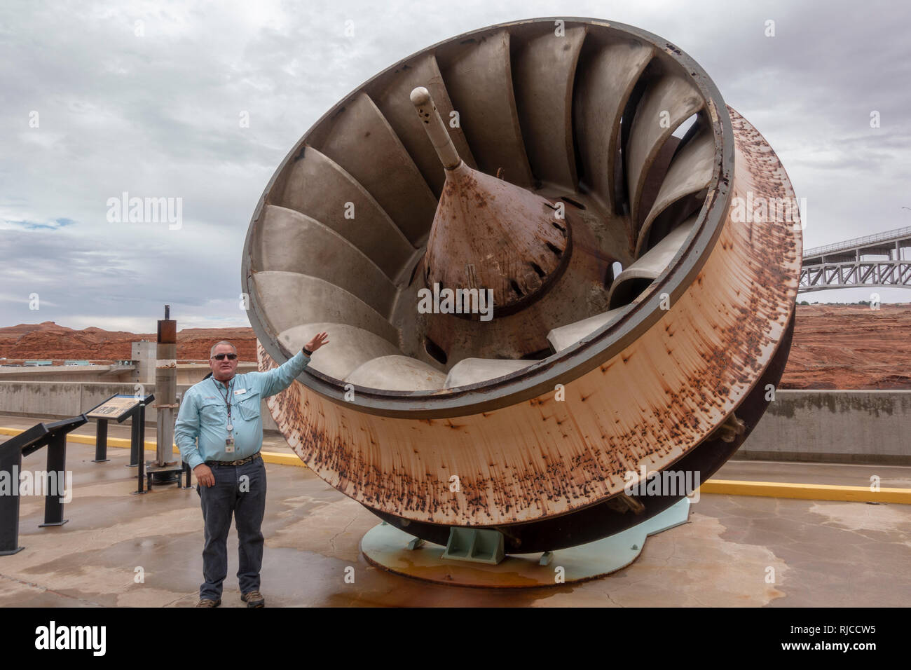 Tour guide standing beside one of the original 8 turbine runners used Glen Canyon Dam, as seen on the tour, Page, Arizona, United States. Stock Photo