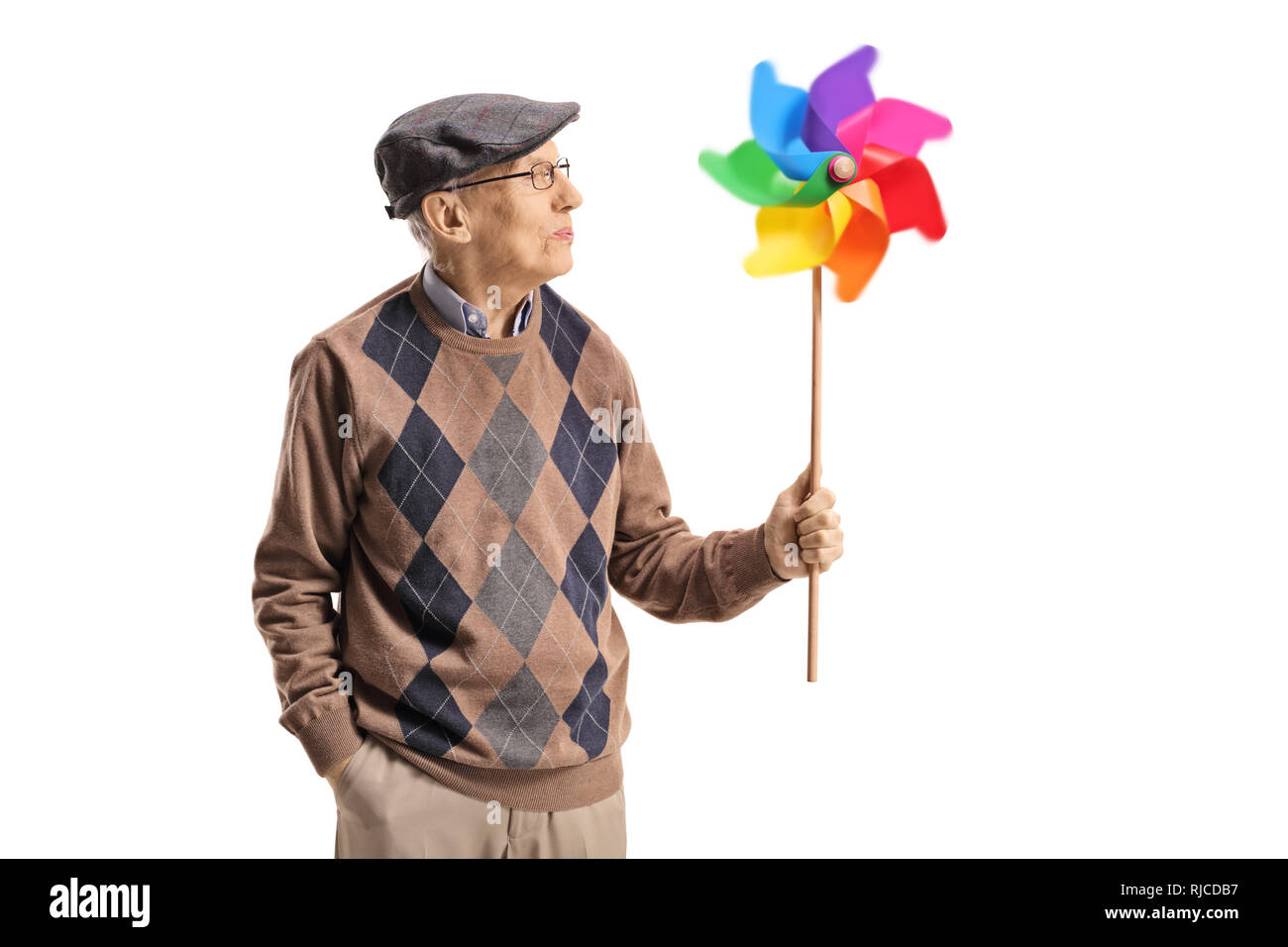 Senior man holding a spinning pinwheel and looking at it isolated on white background Stock Photo