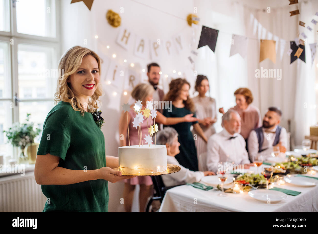 A young woman holding a birthday cake on an indoor party Stock Photo ...