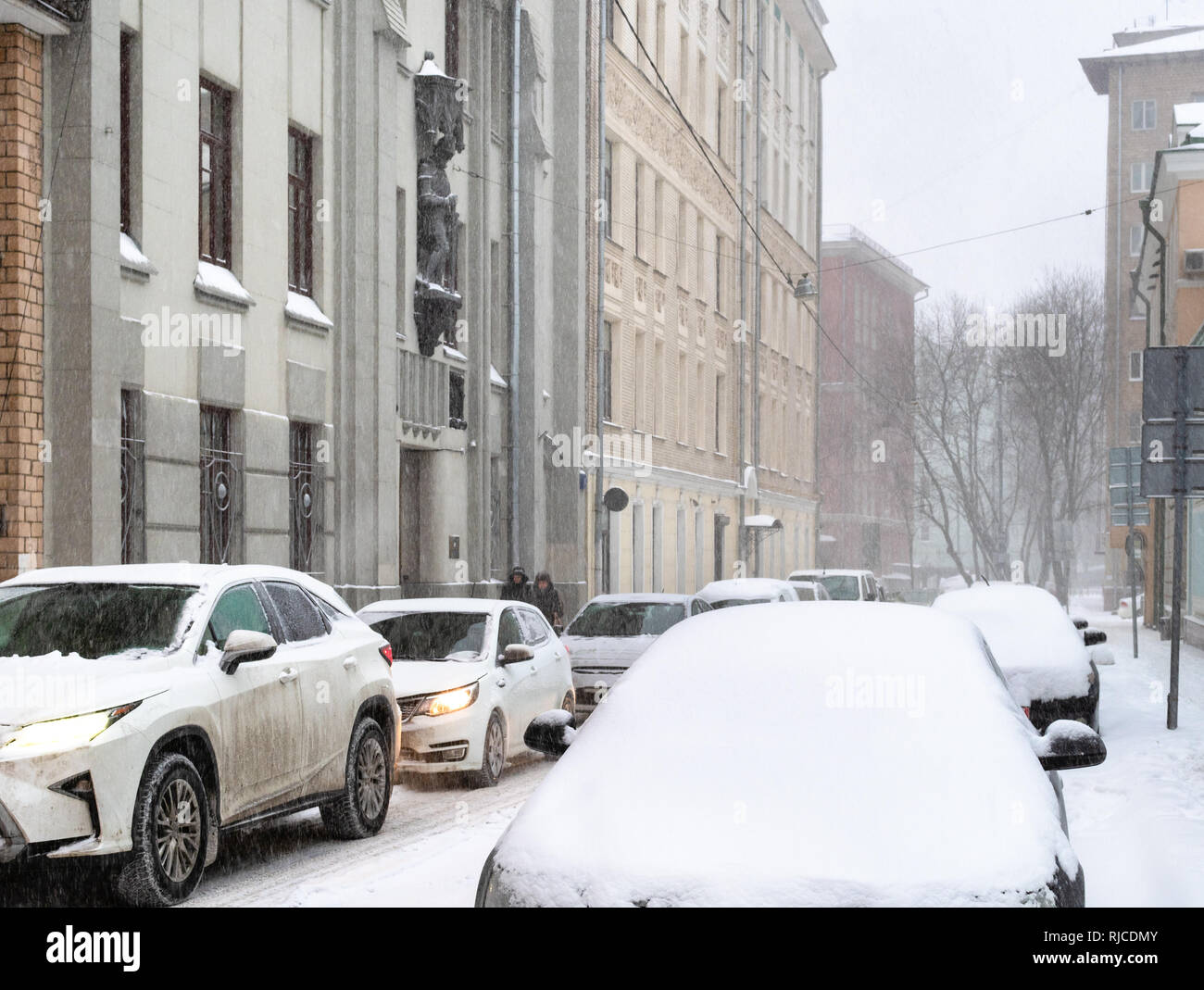 car traffic at narrow street in Moscow city in snowfall in snowy winter day Stock Photo