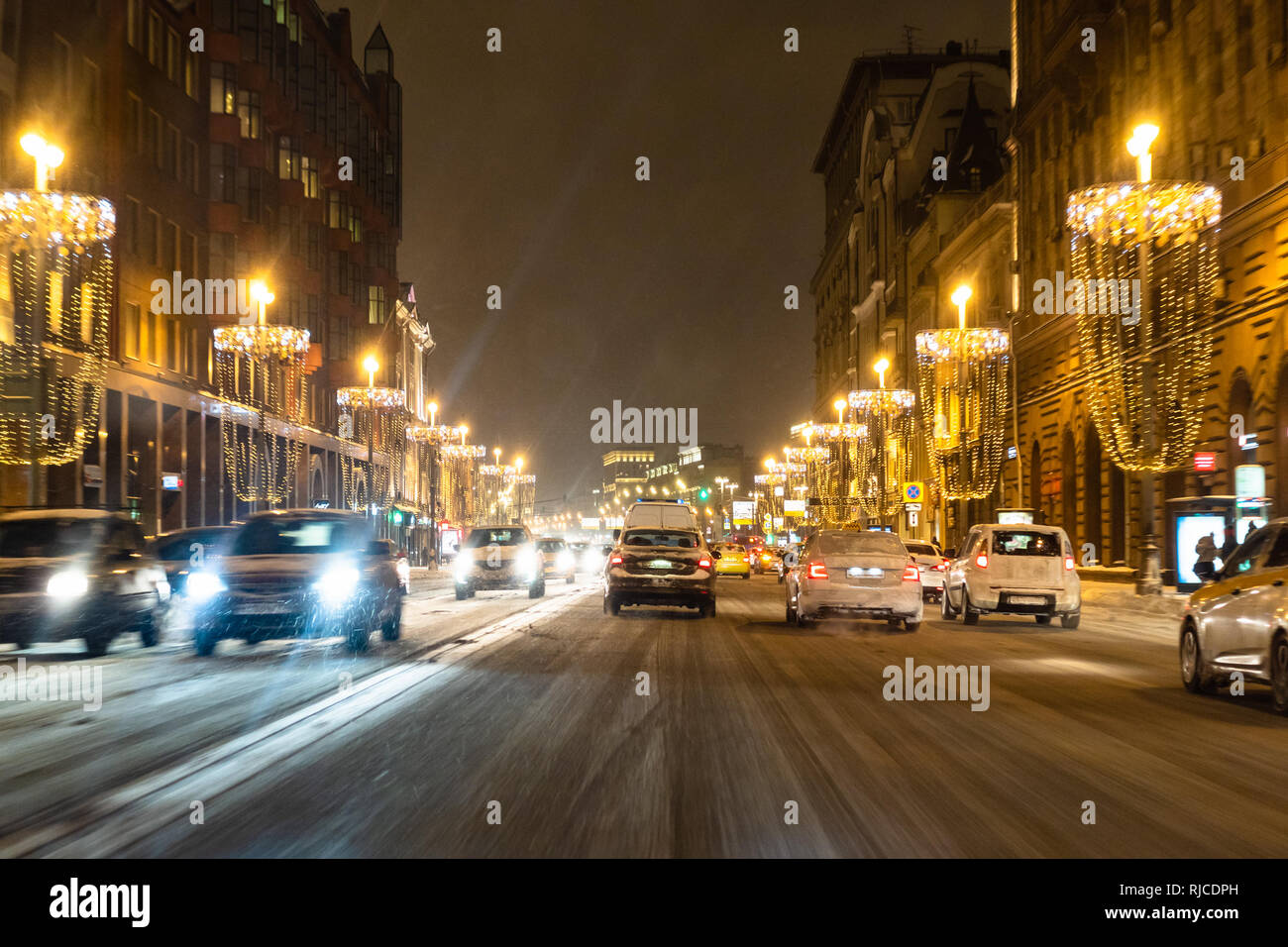 cars drive on slippery Tverskaya street in Moscow city at snow winter night Stock Photo