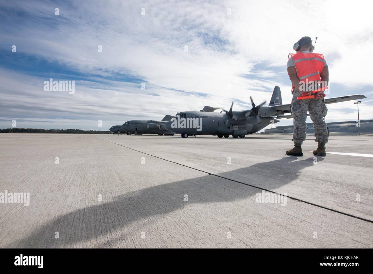 POPE ARMY AIRFIELD, N.C. — Senior Airman Mycojeb Quiocho, a crew chief in the 43d Air Mobility Squadron here, waits to marshall a C-130H Hercules from the Georgia Air National Guard's 165th Airlift Wing as it prepares to launch with a load of Army paratroopers from Fort Bragg's 27th Engineer Battalion (Airborne) during joint airdrop training on Green Ramp here Jan. 10, 2018. Airmen in the 43d AMS and 43d Air Base Squadron here supported both visiting aircrews and Army units throughout the training. The 43d Air Mobility Operations Group, which is part of Air Mobility Command, powers airlift tra Stock Photo