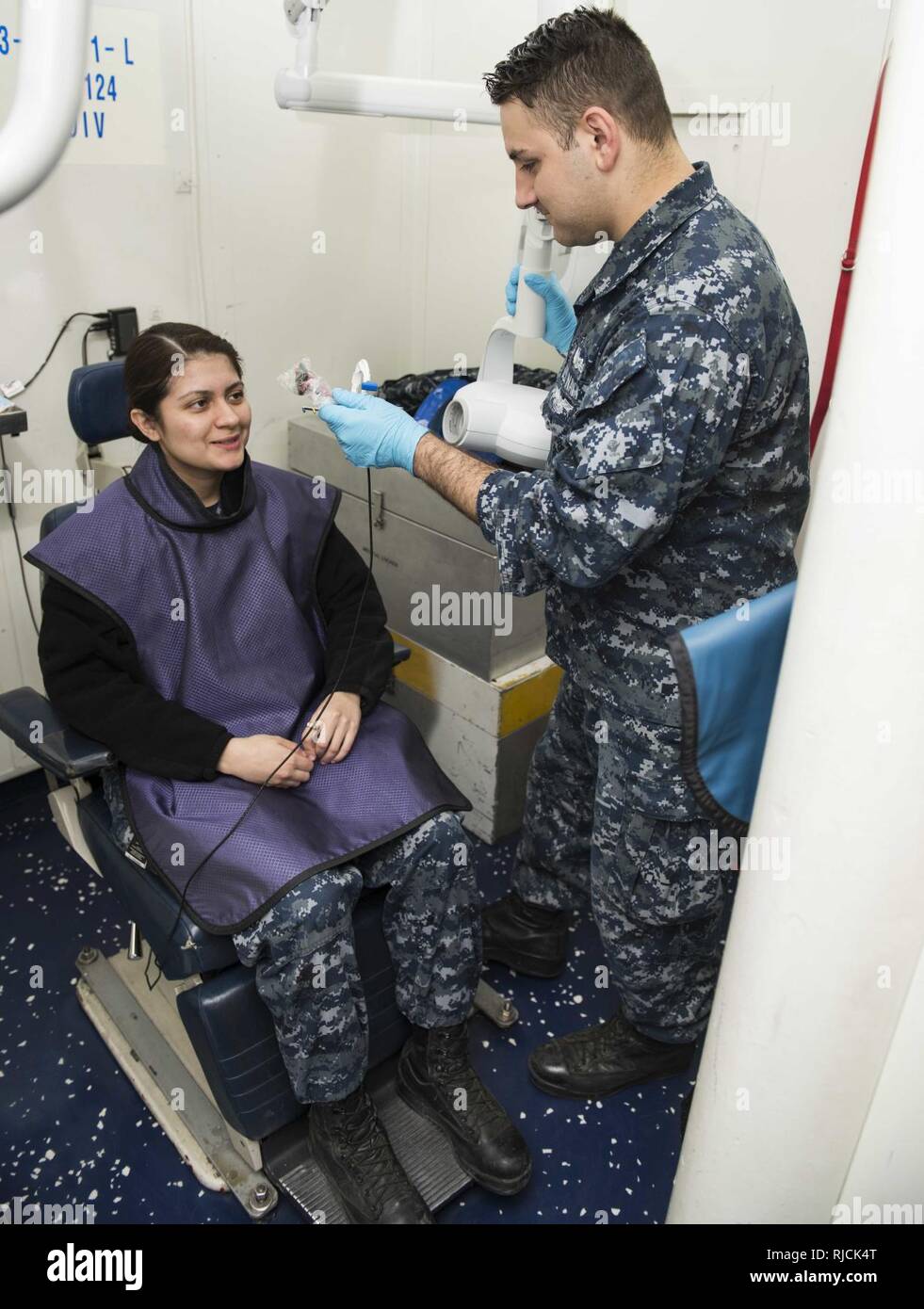 PORTSMOUTH, Va. (Jan. 11, 2018) Hospitalman Dustin Garner, right, prepares Aviation Structural Mechanic Airman Jaquelin Ramirez for an X-ray aboard the aircraft carrier USS Dwight D. Eisenhower (CVN 69). Eisenhower is undergoing a Planned Incremental Availability (PIA) at Norfolk Naval Shipyard during the maintenance phase of the Optimized Fleet Response Plan (OFRP). Stock Photo