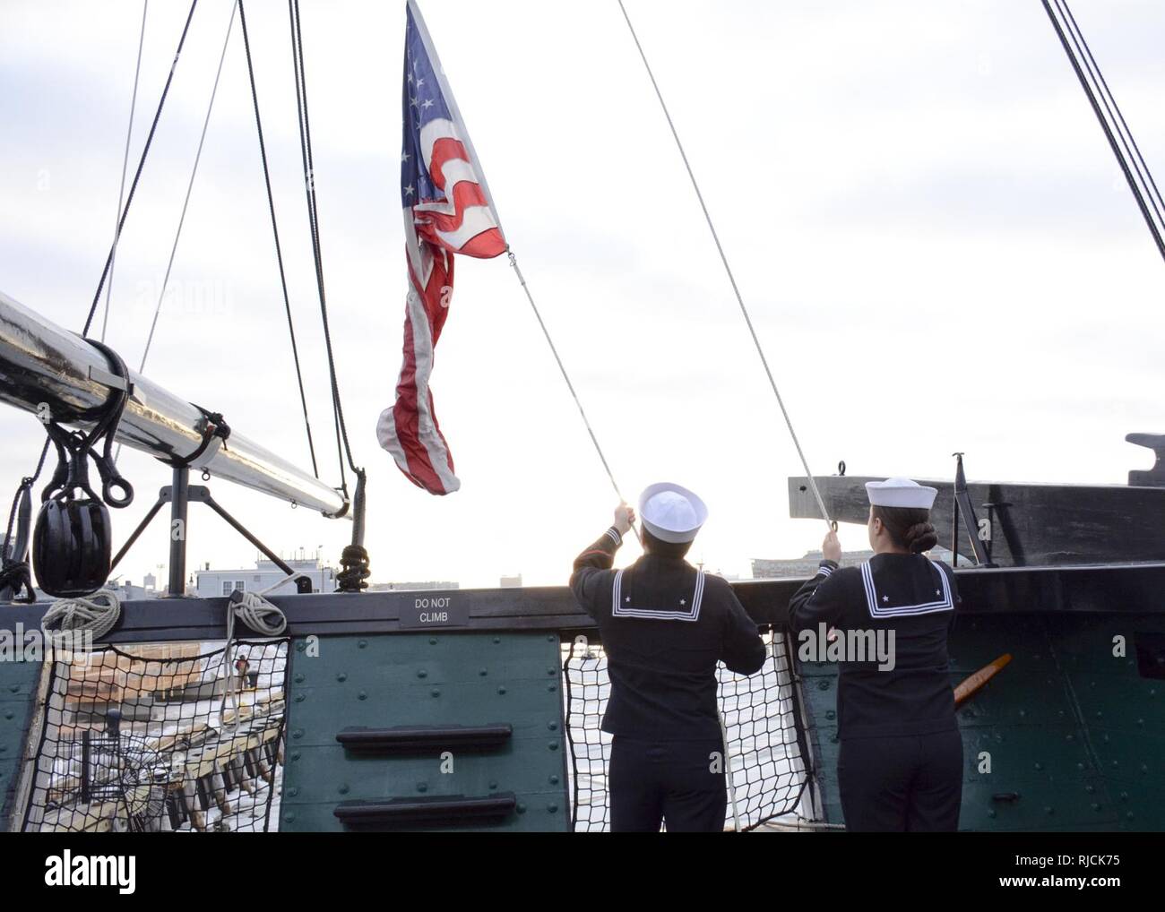 BOSTON (Jan. 11, 2018) Boatswain's Mate 2nd Class Cory Van Beveren and Seaman Ashley Watson raise the ensign during morning colors aboard USS Constitution. Stock Photo