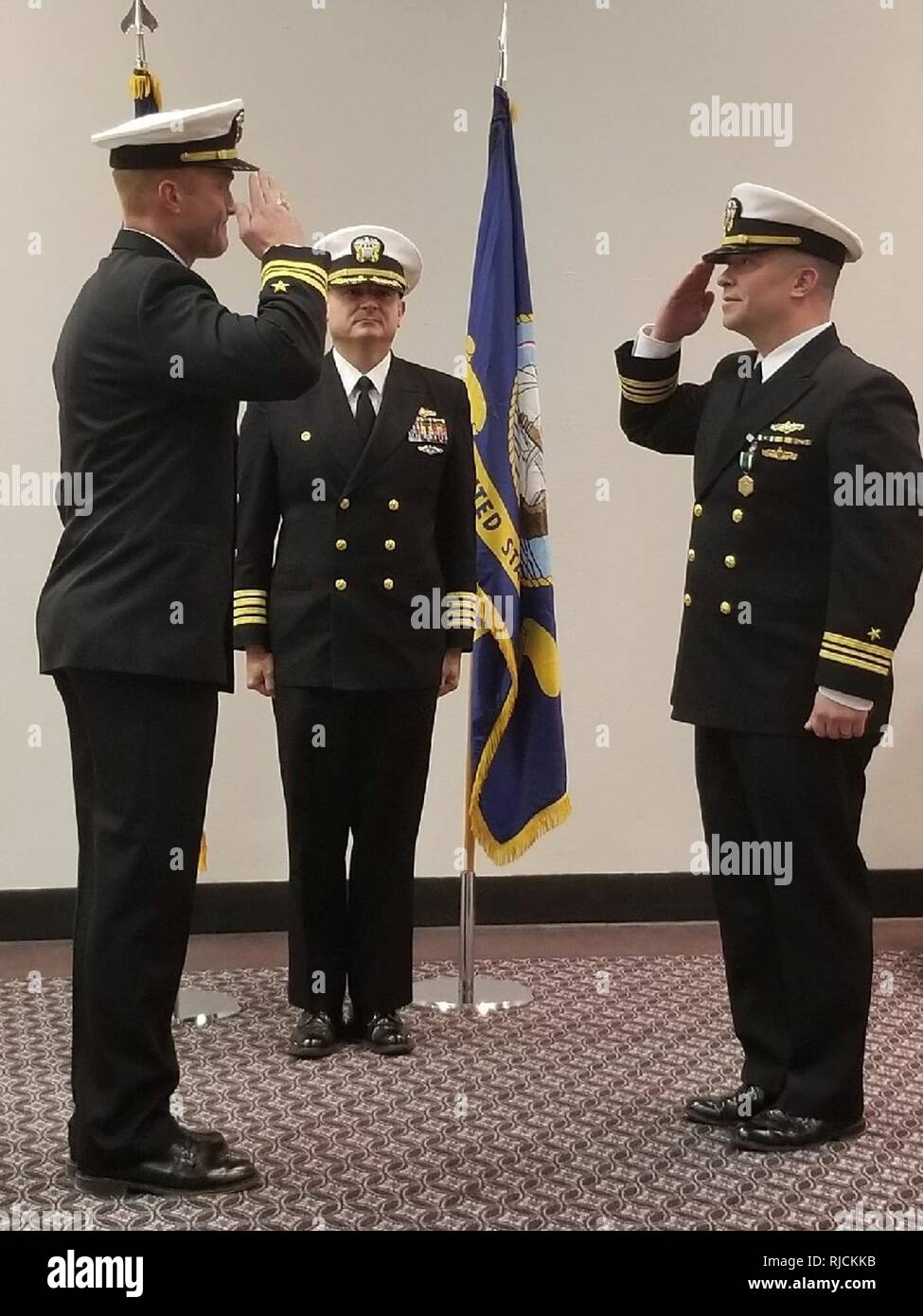 SAN ANGELO, Texas – Capt. Bill Lintz (center) presides over the change of charge ceremony salute between Lt. Cmdr. Christopher Allen (right) and Lt. Cmdr. Austin Maxwell. Allen transferred responsibility as the officer in charge of Center for Information Warfare Training (CIWT) Detachment Goodfellow to Maxwell. Stock Photo