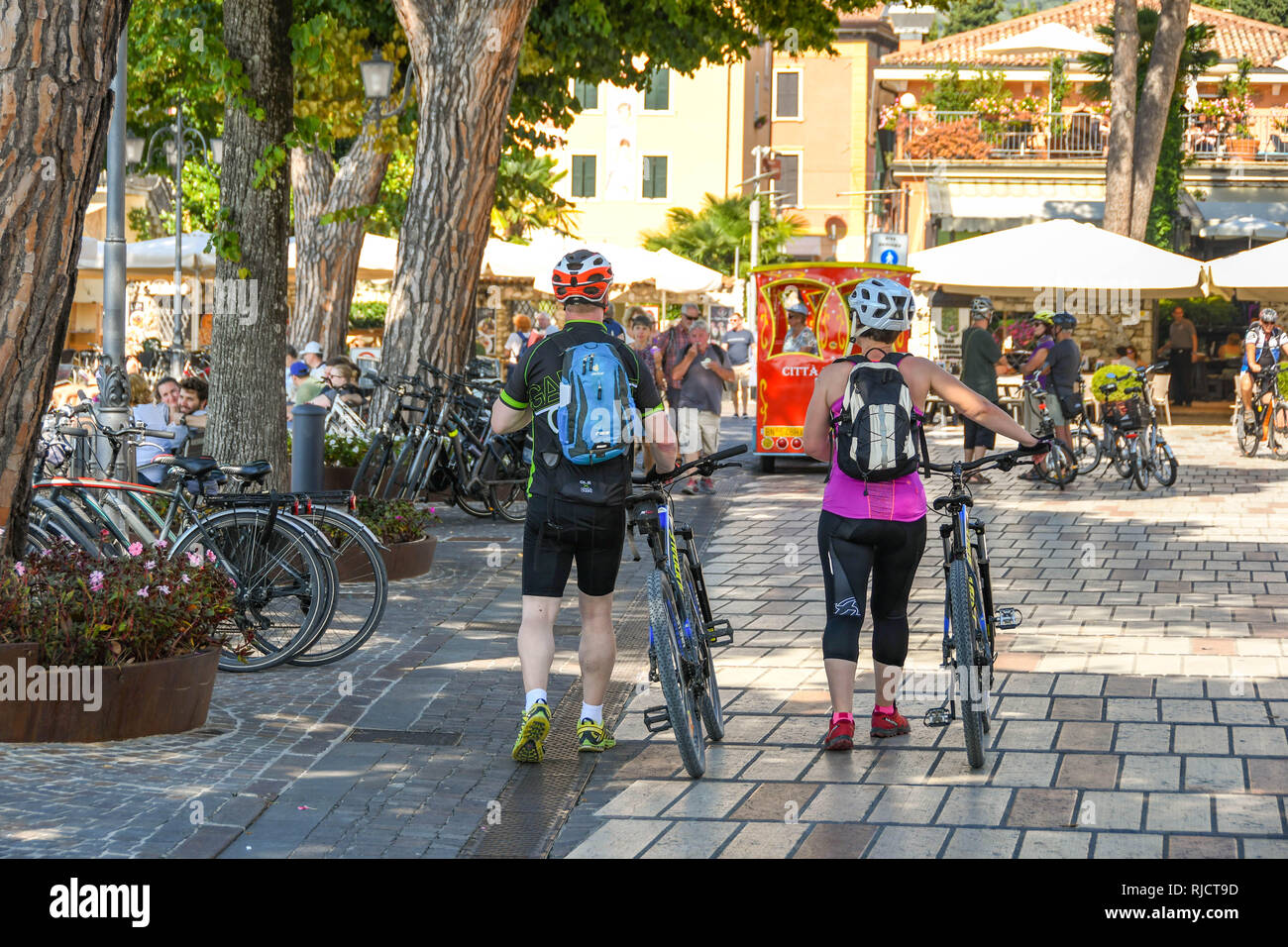 GARDA, ITALY - SEPTEMBER 2018: Cyclists wheeling their bikes through Garda on Lake Garda. Stock Photo