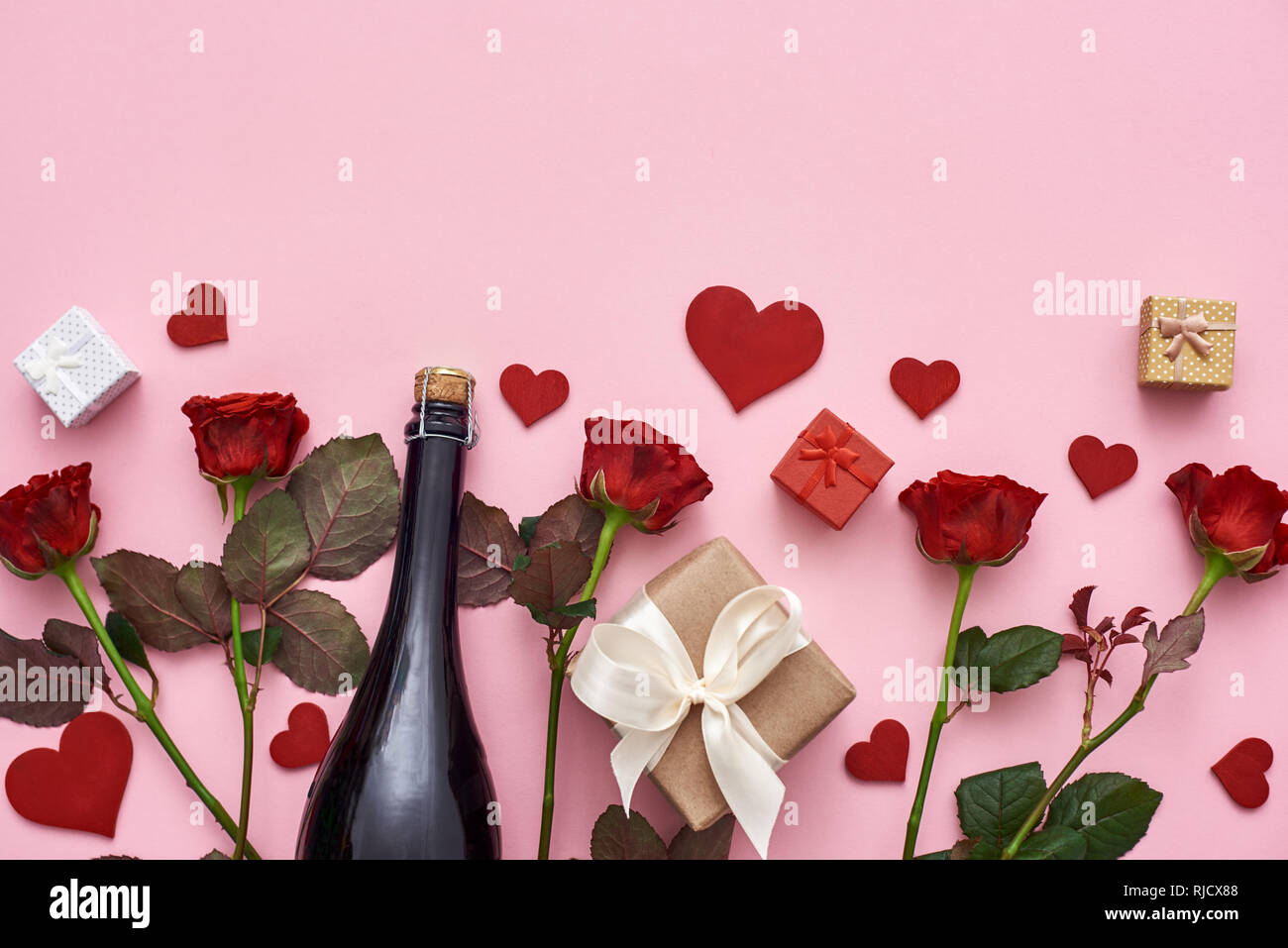 Let us celebrate Set of red roses, champagne, gift boxes and hearts. Pink background Stock Photo