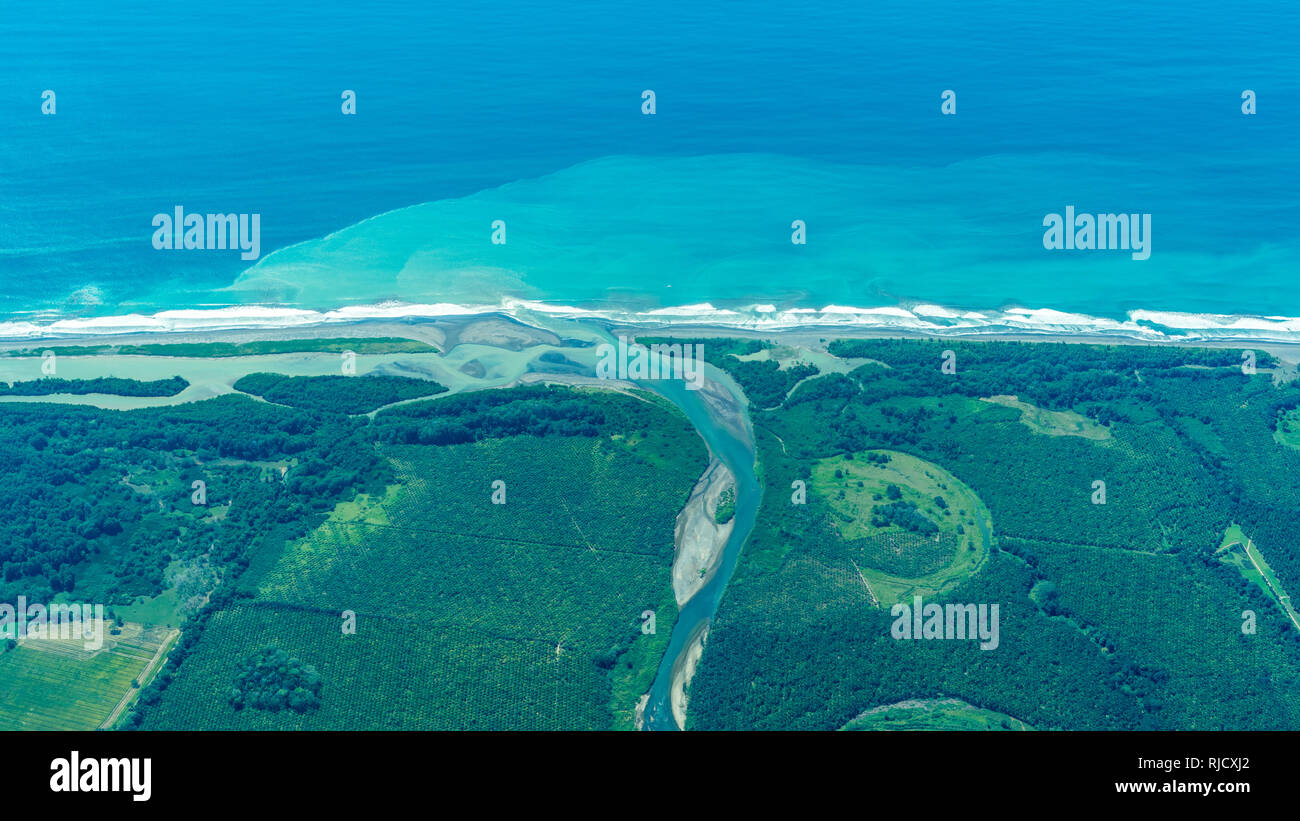 An aerial photo of the beautiful landscape of the Pacific coast of Costa Rica. Turquoise blue ocean and a estuary of a river can be seen. Stock Photo