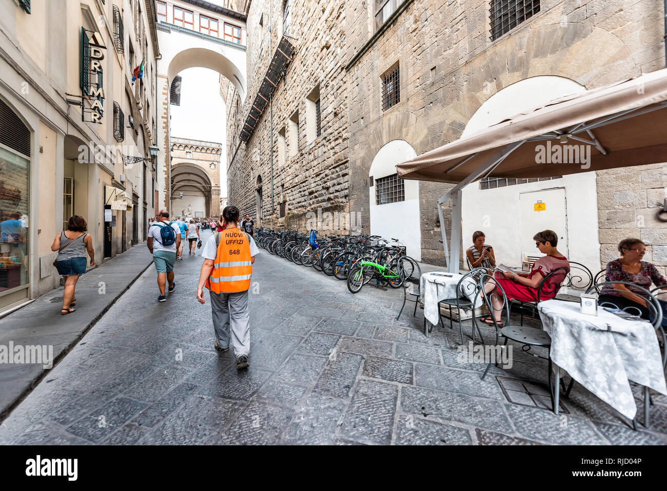 Firenze, Italy - August 30, 2018: People man Uffizi worker walking with uniform and tourists sitting in historic street in Florence Renaissance city P Stock Photo
