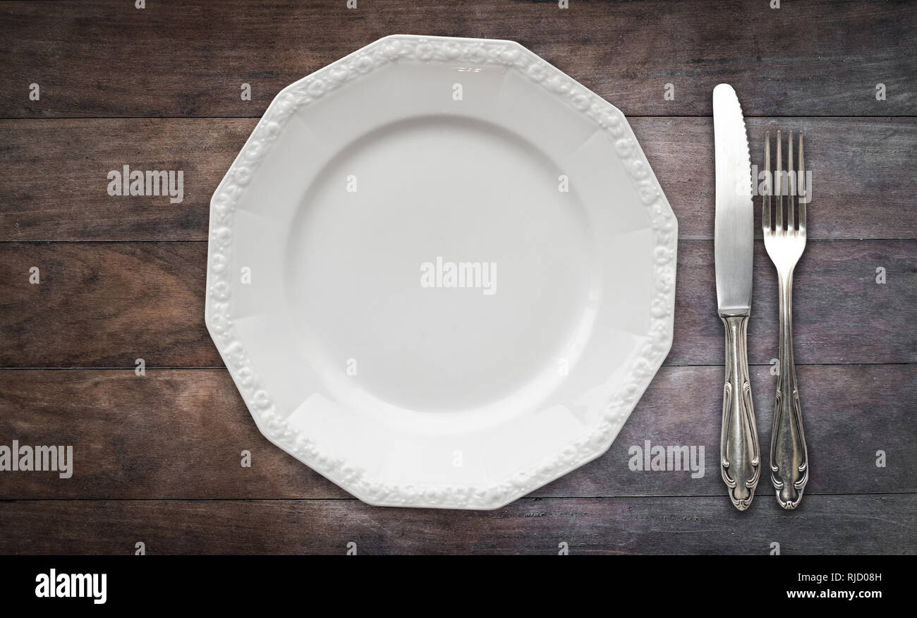 empty plate, fork and knife on wood table, flat lay Stock Photo