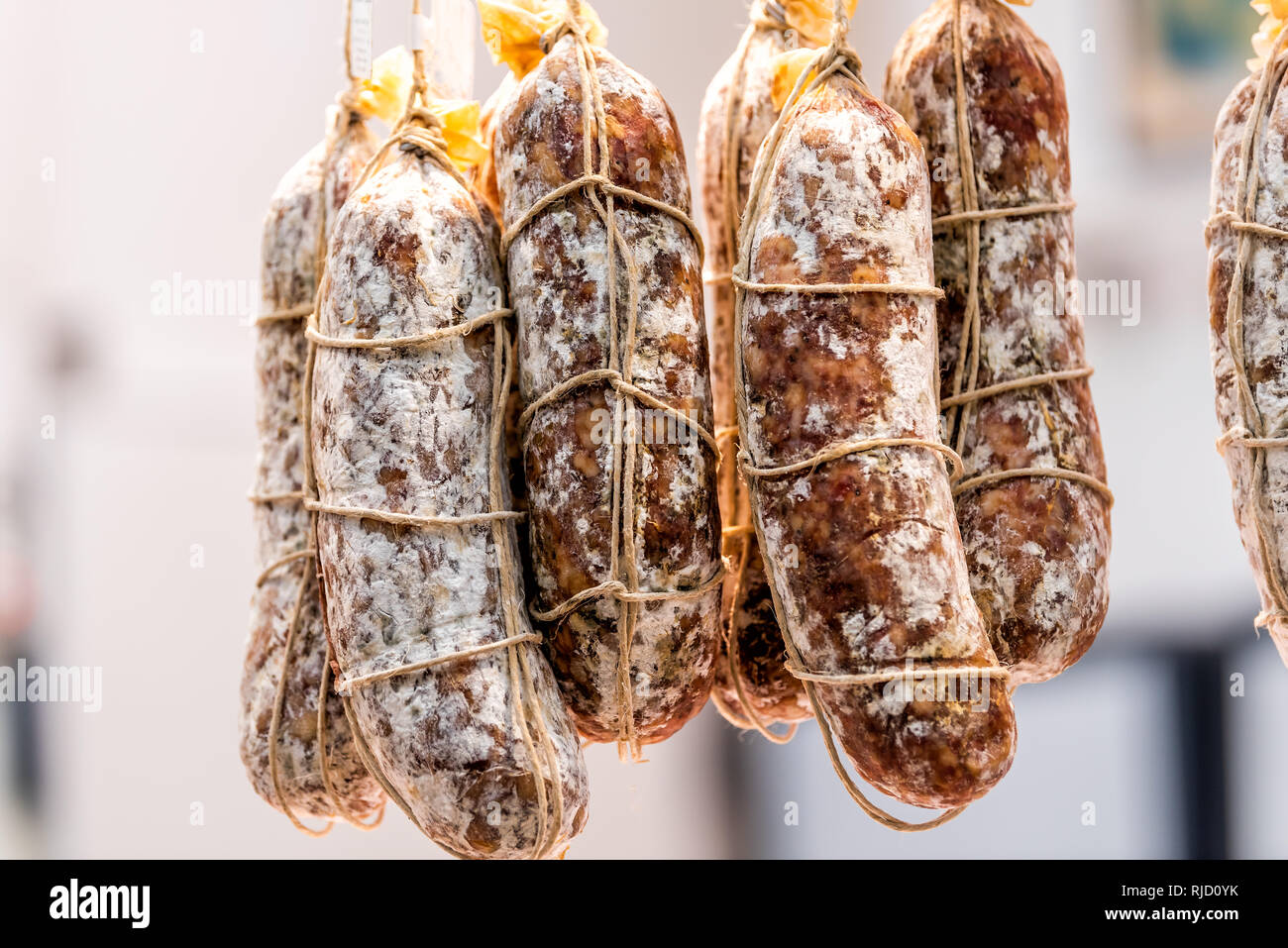 Closeup of salami rolls sausages hanging on string on display in a market shop butcher background group in market in Florence, Italy Stock Photo