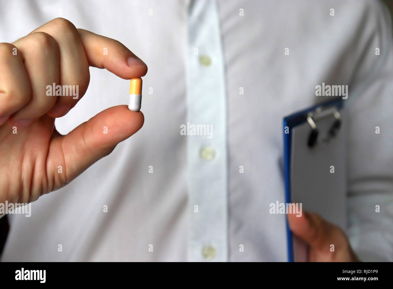 Doctor with pill, man holding capsule. Concept of medications, vitamins, cold and flu treatment, pharmacy Stock Photo