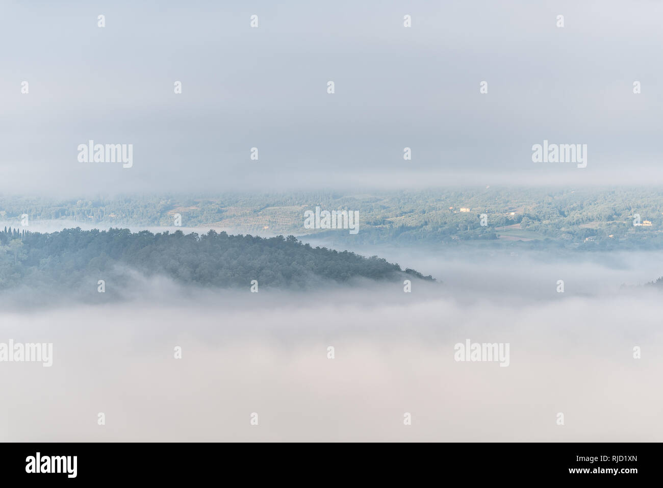 Chiusi Scalo mountain mist fog sunrise and villas houses in Umbria and Tuscany in Italy with soft clouds covering blanketing inversion in summer Stock Photo