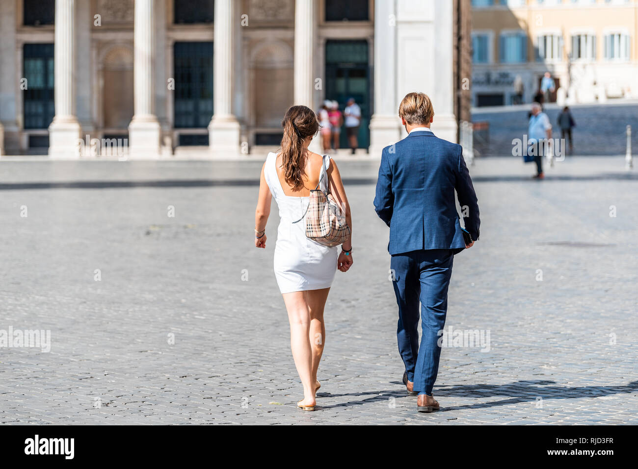 Rome, Italy - September 4, 2018: Local Italian man couple in city street work businessman and woman walking on piazza square in suit by Palazzo Wedeki Stock Photo