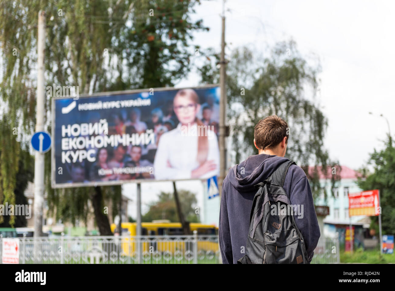 Rivne, Ukraine - July 28, 2018: Young Ukrainian man walking in front of political advertisement ad banner sign for Yulia Tymoshenko for president by s Stock Photo
