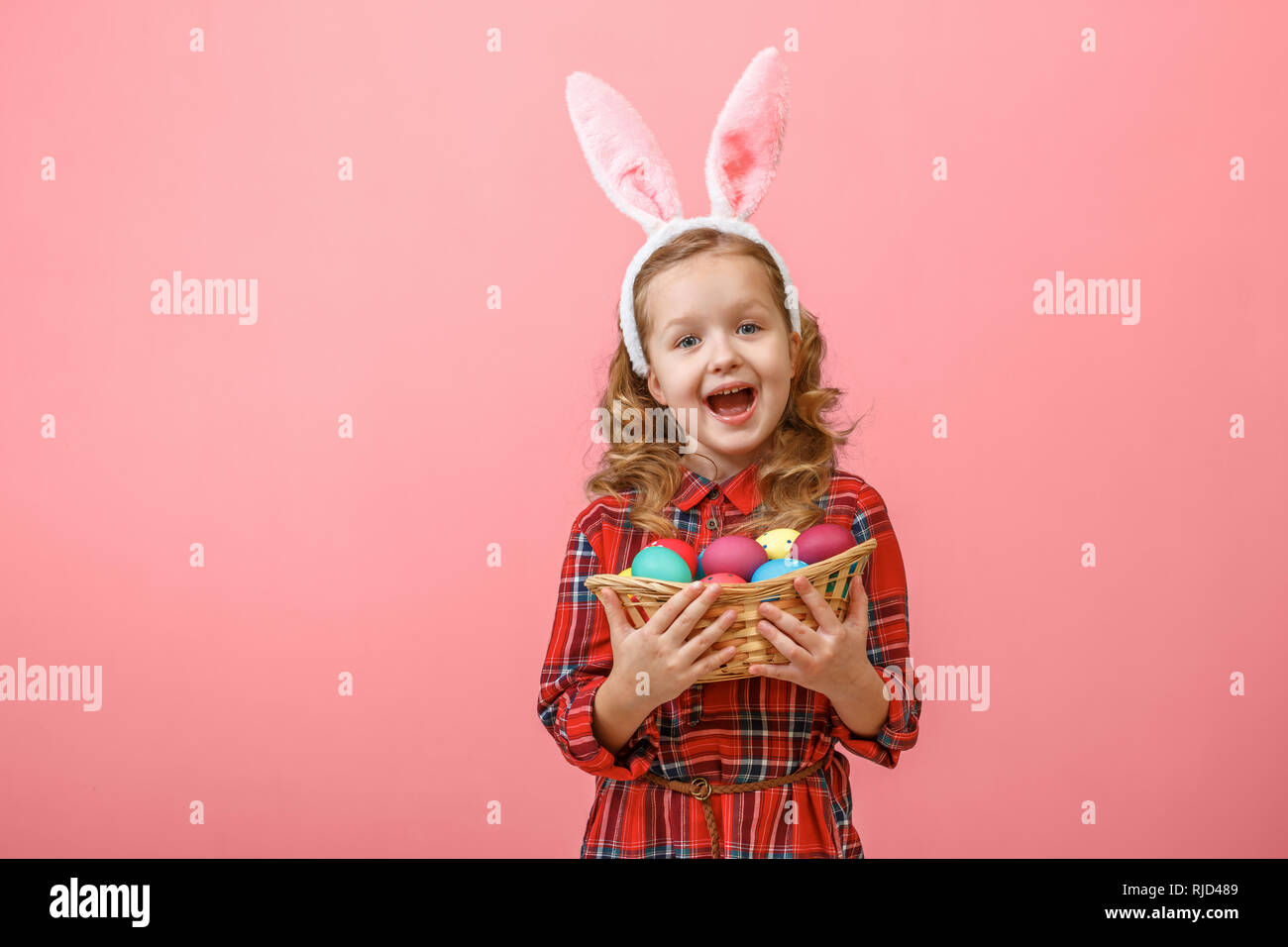 Cute little child girl with bunny ears holding basket of Easter eggs on ...