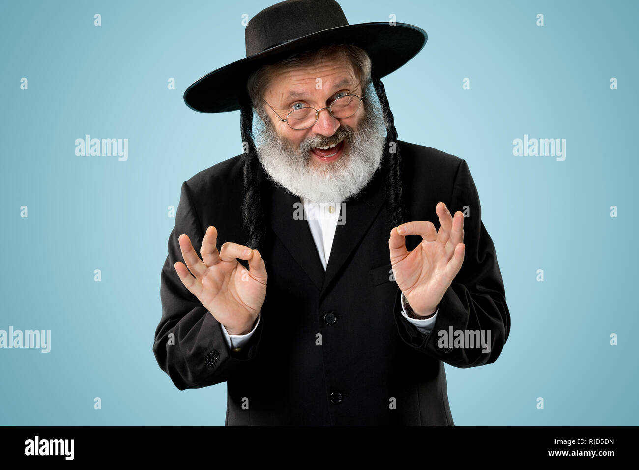 Portrait of old senior orthodox Hasdim Jewish man with wooden Grager Ratchet at Jewish festival of Purim at studio. The purim, jewish, festival, holiday, celebration, judaism, pastry, tradition, cookie, religion concept. Stock Photo