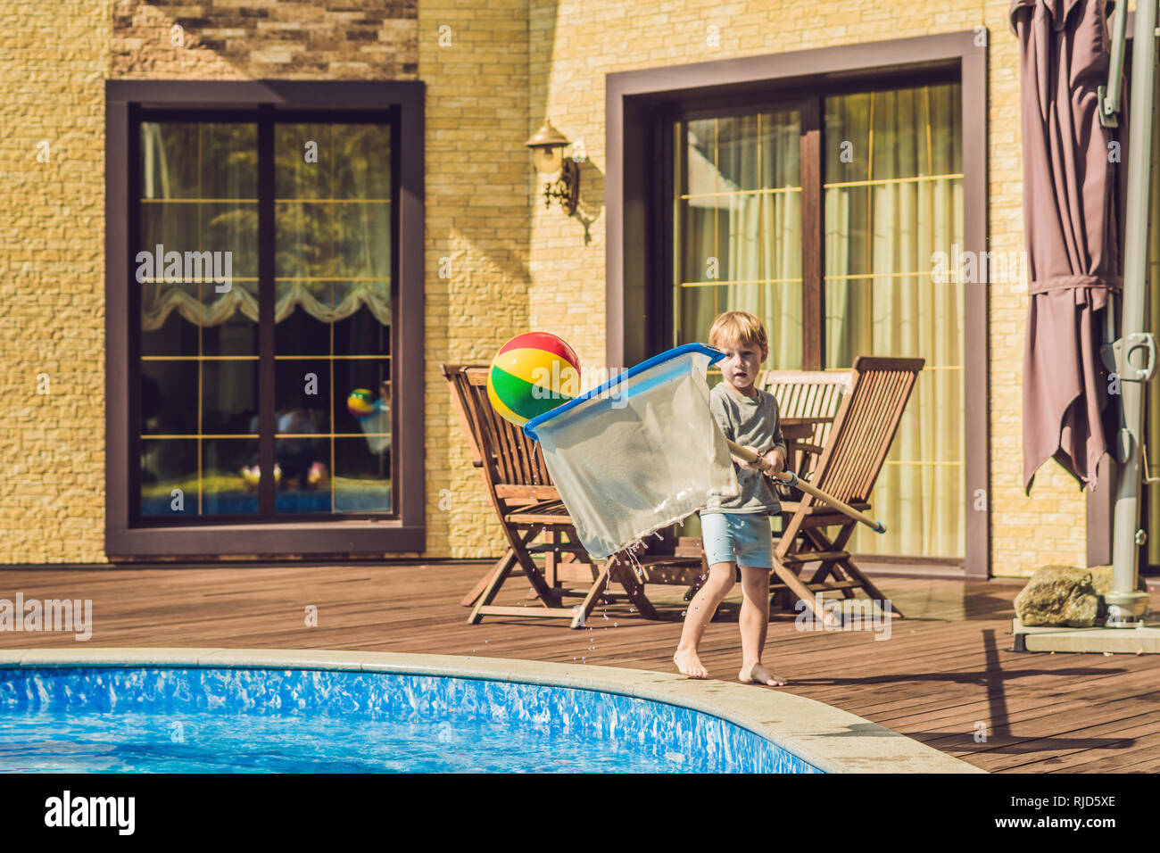 The Toddler Boy Cleans The Pool And Pulls The Ball Out Of
