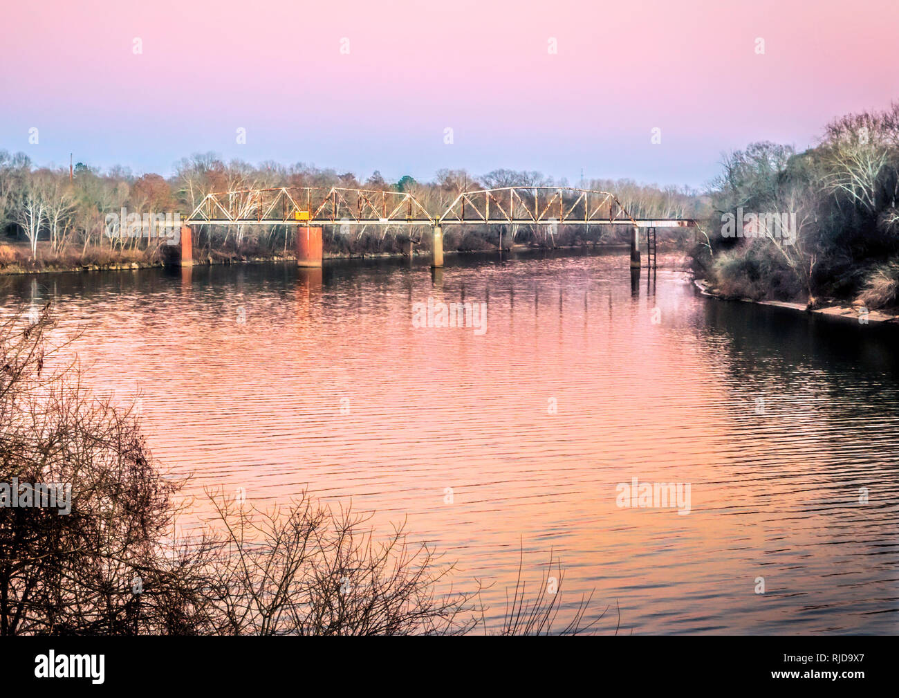 The sun sets on the CSX railroad bridge over the Alabama River, Feb. 14, 2015, in Selma, Alabama. The bridge is a Parker through truss swing bridge. Stock Photo