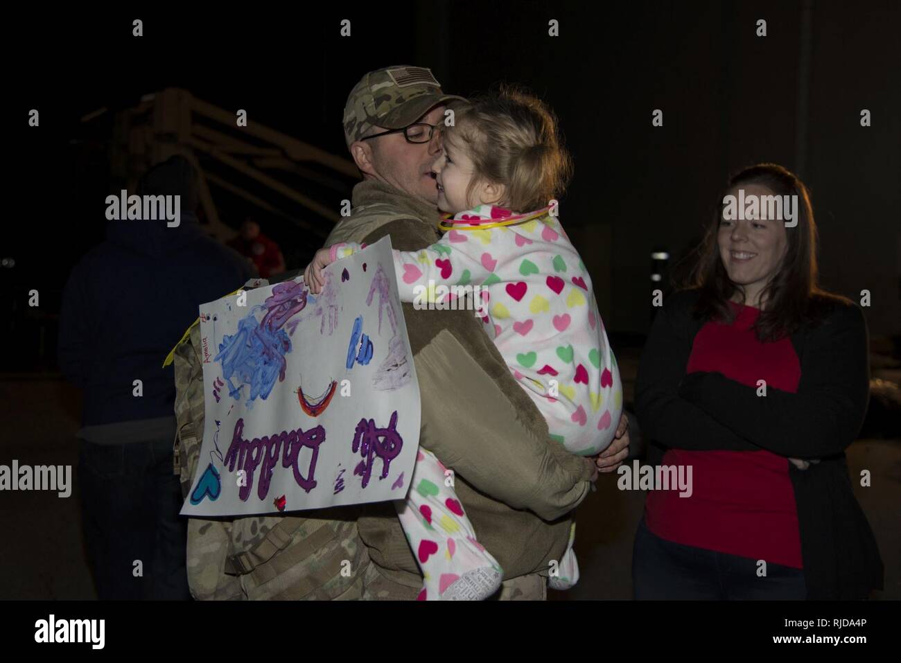 Master Sgt. Michael Johnson, 436th Security Forces Squadron defender, hugs his daughter, Amelia, as his wife, Kelly, looks on Jan. 21, 2018, at Dover Air Force Base, Del. The Johnson family was reunited after a six-month deployment to the Middle East. Stock Photo