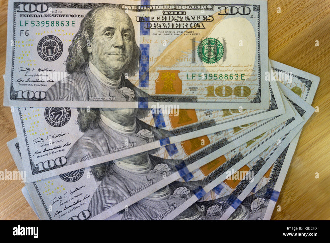 crolled stack of 100 new dollar bills on wooden background. Stock Photo