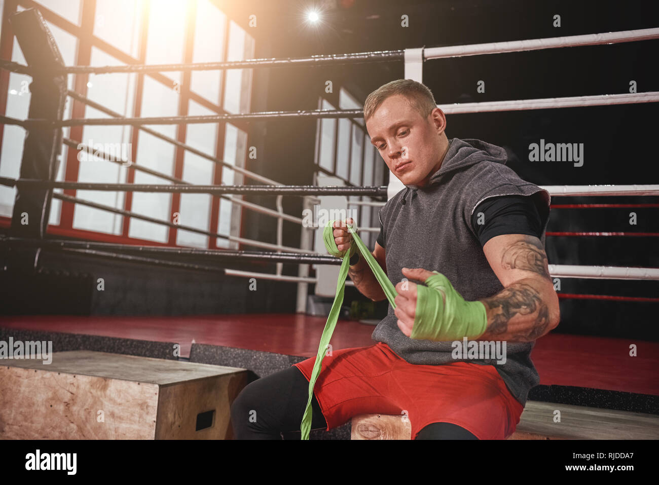 Boxing defence. Confident athletic man wrapping hands with green boxing