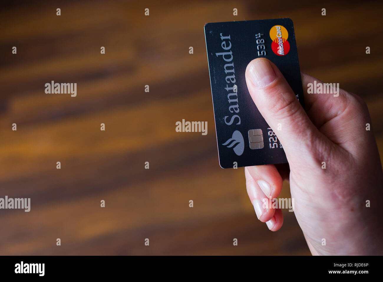 Person is paying with a Santander Bank black credit card with MasterCard logo Stock Photo