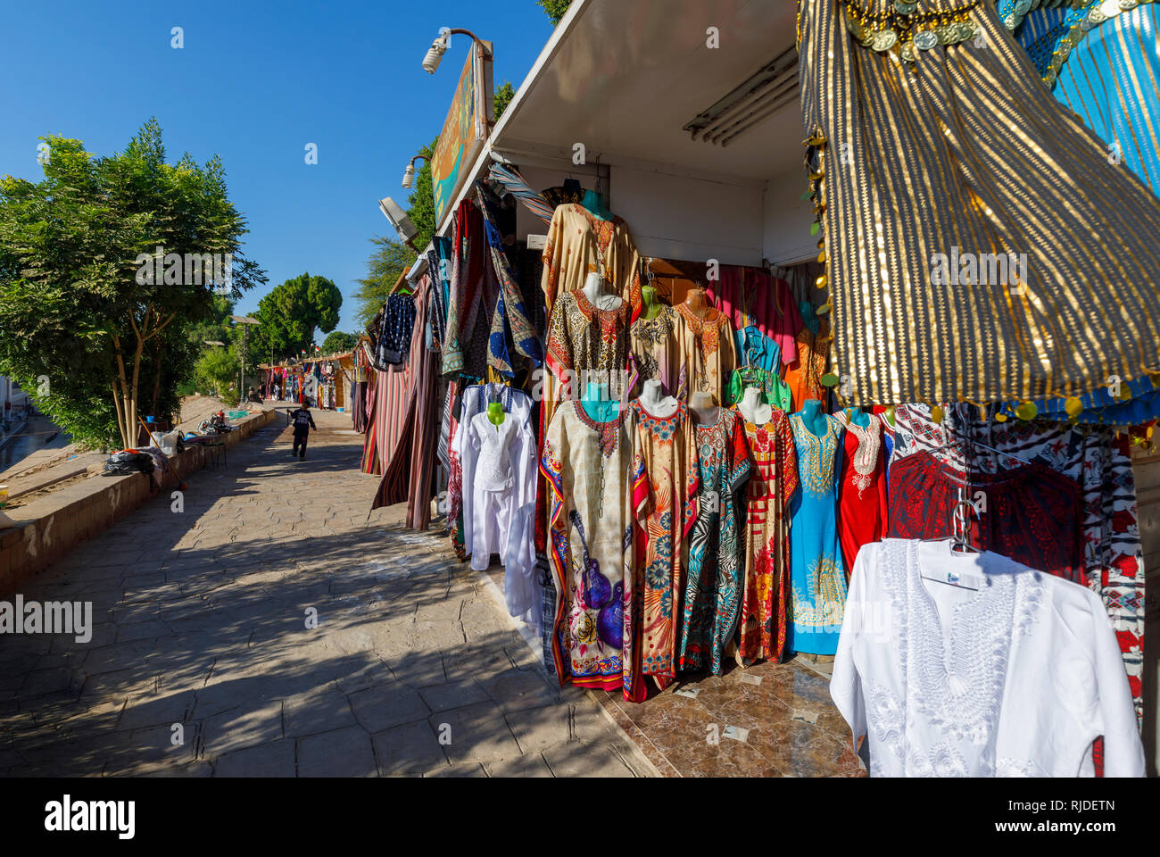 Market on the banks of the Nile by the Temple of Kom Ombo, Upper Egypt selling traditional colourful galabeyas as souvenirs for tourists from cruises Stock Photo